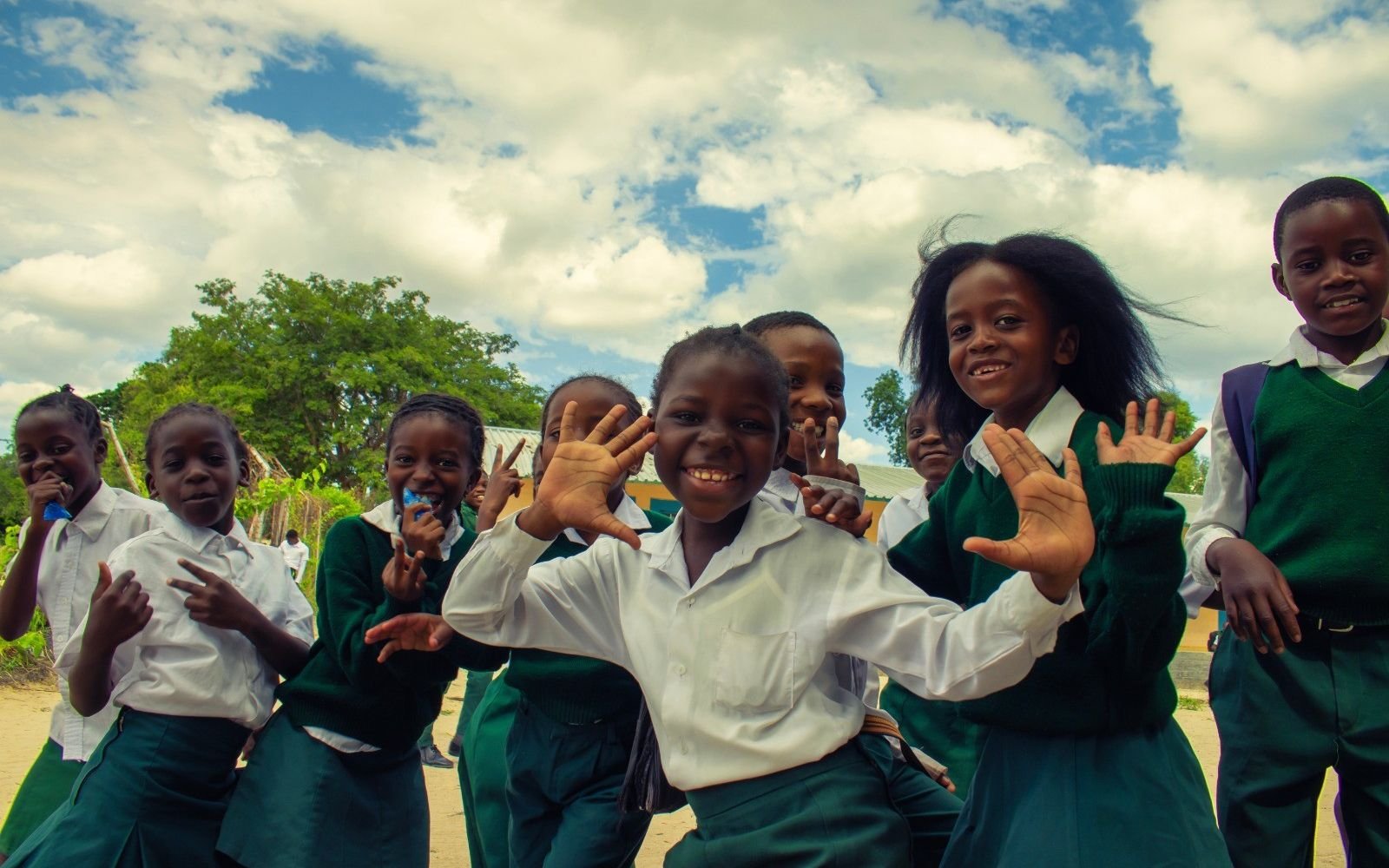 Children in school uniform waving outdoors